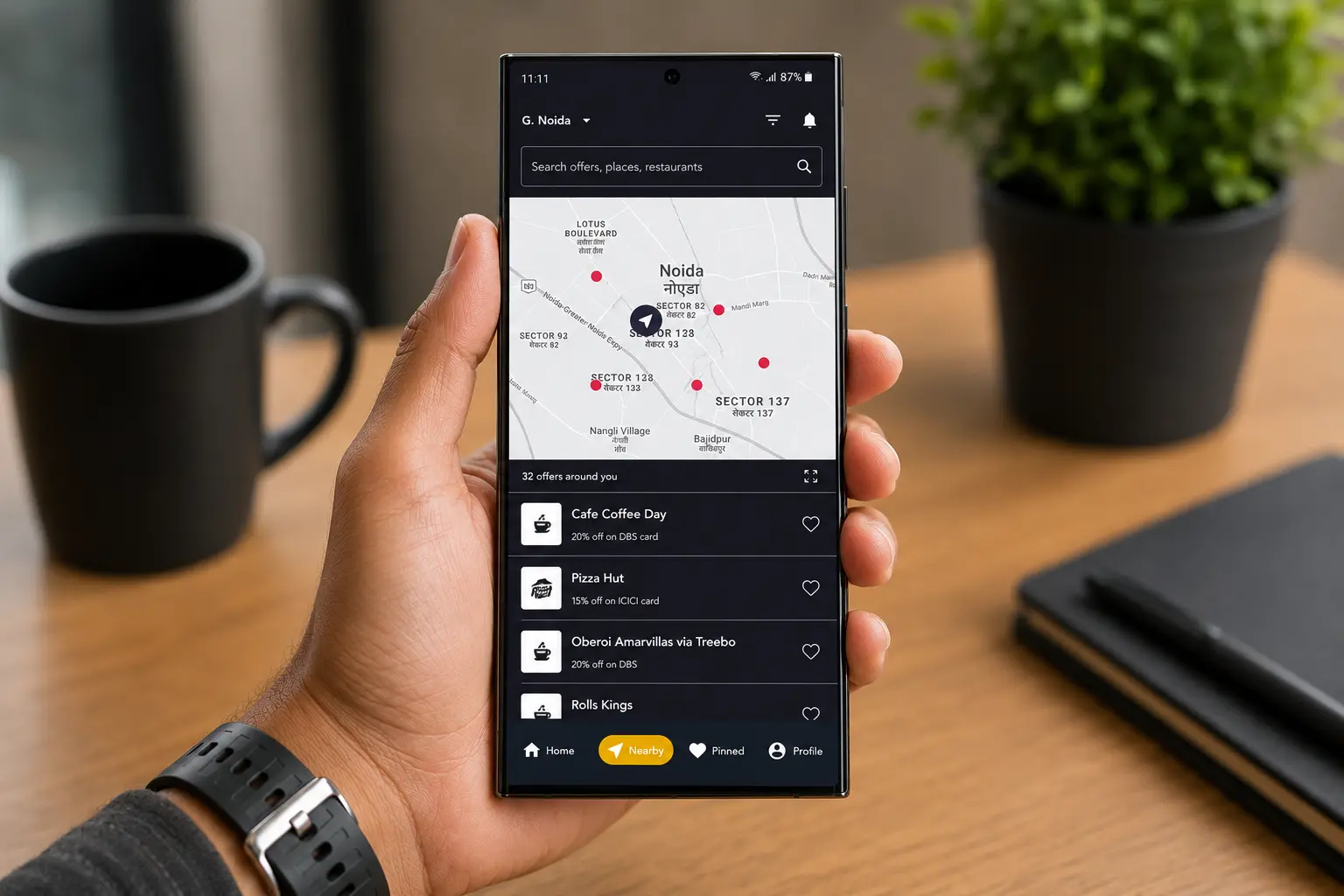 A hand holding a phone that shows Cardinal’s Nearby screen: a map with offer pins and a list of the 32 offers around you